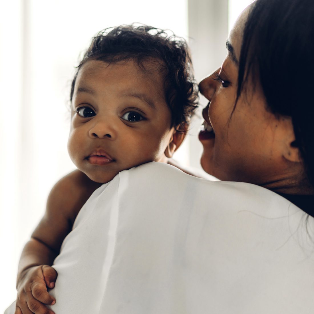 A woman holding her newborn son over her shoulder