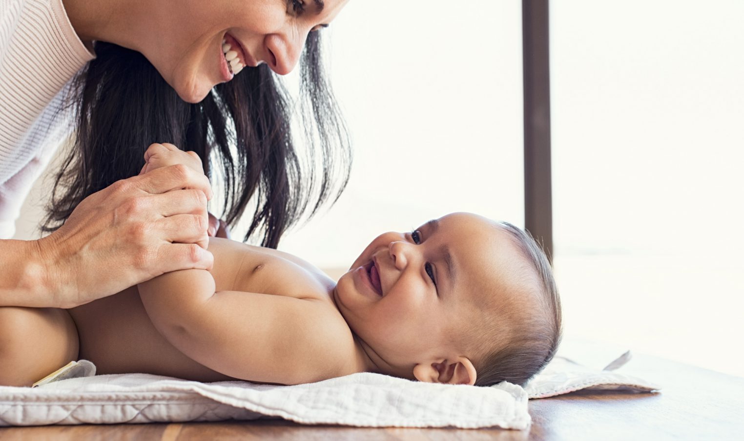 Mother smiles at her baby lying on his back